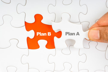 Fototapeta premium Hand holding piece of jigsaw puzzle with word PLAN A & PLAN B. Selective focus