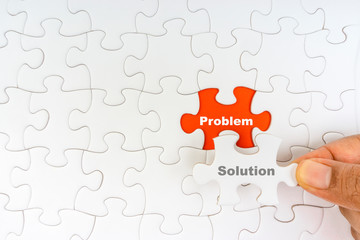 Hand holding piece of jigsaw puzzle with word PROBLEM SOLUTION. Selective focus