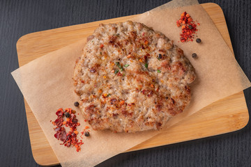 meat patty for a burger on a wooden board, close-up, top view