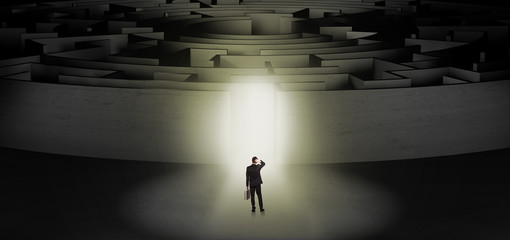 Businessman getting ready to enter a concentric labyrinth with lighted entrance concept
