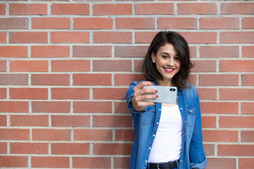 Young brunette girl with shirt and cowboy panstalon on brick wall