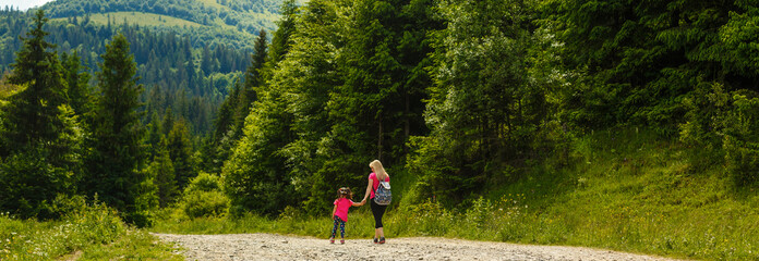 Mother and little girl walking along the mountain road