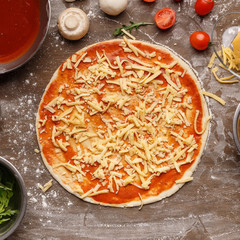 Pizza preparation. Raw dough with grated cheese