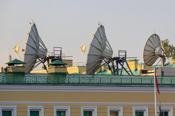 Satellite parabolic antennas on building roof closeup in sunny morning