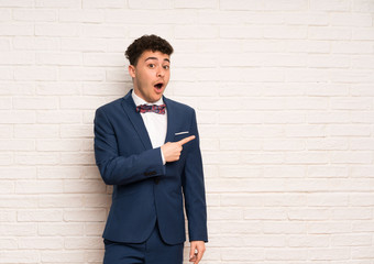 Man in suit and bow tie surprised and pointing side