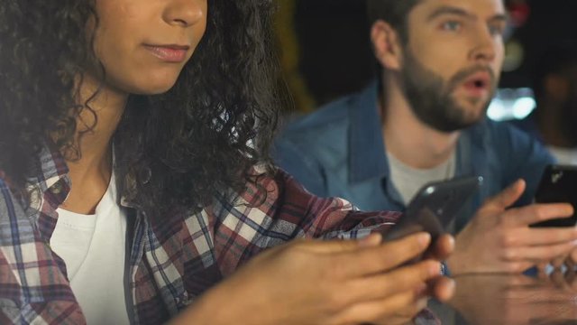 Man and woman checking winner combination on smartphones, watching lottery