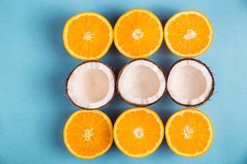 Juicy ripe oranges and white coconut halves lined with a square on a bright blue background.Top view, flat lay