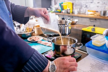 Chef pours the required amount of broth into the pan, which stands on the scales. Master class in the kitchen. The process of cooking. Step by step. Tutorial. Close-up