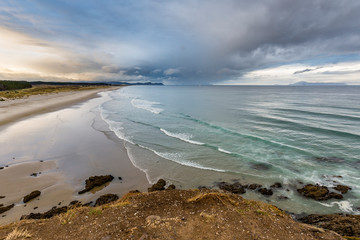 Overlooking Northland Beach with incoming Pacific waves and a lonley surfer, New Zealand