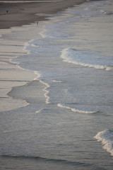 slow incoming Pacific waves at sunset with reflecting sunlight, lonley fishermen, Northland, New Zealand