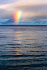 from the clouds Rainbow appears on the ocean horizon