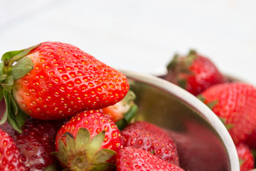 Ripe red strawberry closeup lies in a cup.