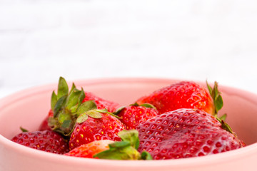 Ripe red strawberry closeup lies in a cup.