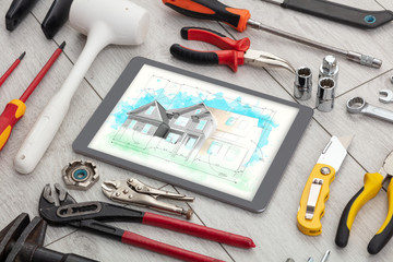 Tablet with construction tools and house plan concept
