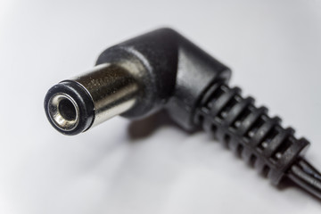 Close-up of 5.5mm x 2.5mm male right angle DC jack barrel connector in partial focus un white isolated background