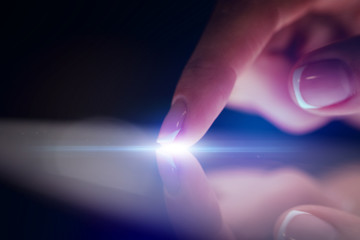 Finger touching tablet with dark background with copyspace
