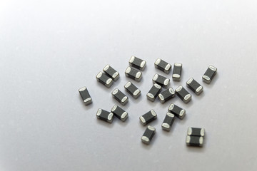 Abstract close-up of grey scattered 0402 SMT surface mount chip ferrite bead power electronics components on white background in random pattern