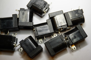 Close-up of scattered DC jack power electronics components on white background in random pattern 