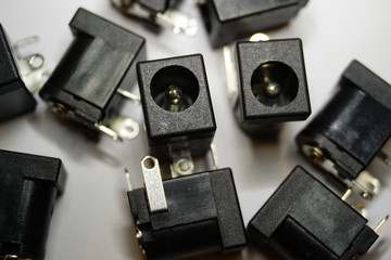 Close-up of scattered DC jack power electronics components on white background in random pattern 