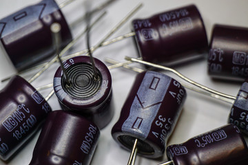 Close-up of scattered electrolytic capacitor power electronics components on white background in random pattern