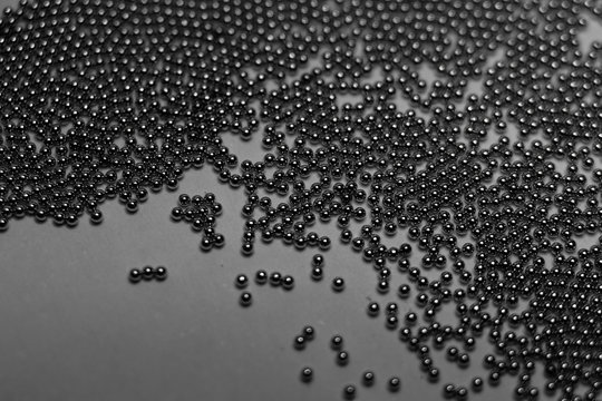 Close-up of industrial electronics assembly manufacturing materials RoHS 0.6mm round BGA soldering balls in partial focus randomly scattered on a gray background