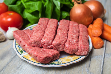 Minced meat for Kebab ready for barbeque. Traditional middle eastern and mediterranean eat. With fresh organic vegetable in the background.