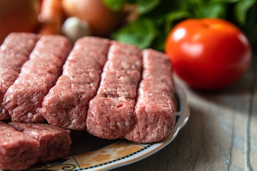 Minced meat for Kebab ready for barbeque. Traditional middle eastern and mediterranean eat. With fresh organic vegetable in the background.