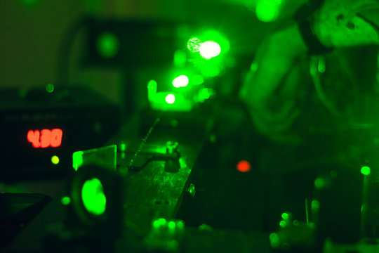 Scientist with glass demonstrates microparticle laser, green laser science research