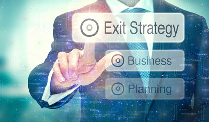 A business man selection a button on a futuristic display with a Exit Strategy concept written on...