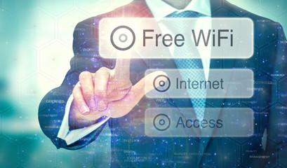 A business man selection a button on a futuristic display with a Free WiFi concept written on it.