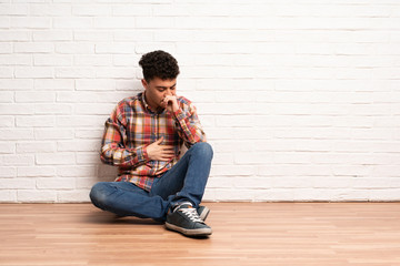 Young man sitting on the floor is suffering with cough and feeling bad