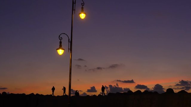 Amazing silhouettes of people strolling backlight at sunset