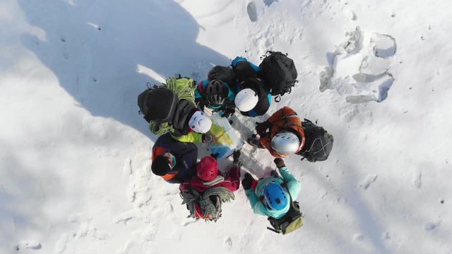 a group of climbers standing in a circle, deliberating how to continue your route, checking the map and compass that keeps their captain