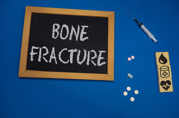 wooden tablet on blue medical table with the word bone fracture