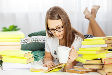 A girl is reading a book with glasses. A student is drinking coffee. Concept of education, hobby and study and world book day