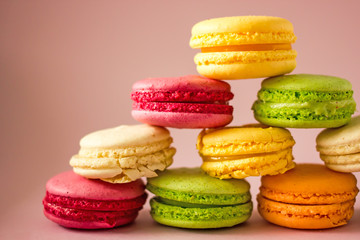 Macarons cakes of different colors on a pink background close-up. Sweet cookies from France, colorful cookies made from flour and egg whites. Confectionery background