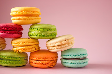 Fototapeta na wymiar Macarons cakes of different colors on a pink background close-up. Sweet cookies from France, colorful cookies made from flour and egg whites. Confectionery background