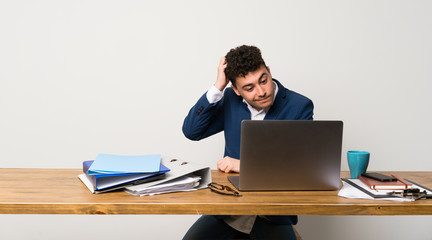 Business man in a office having doubts while scratching head