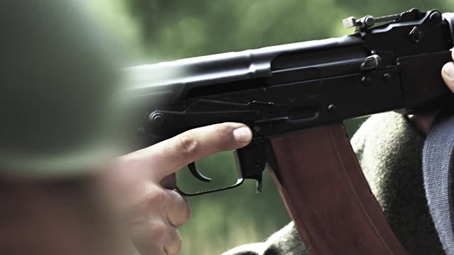 Soldier is aiming while other soldiers passing