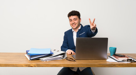 Business man in a office smiling and showing victory sign