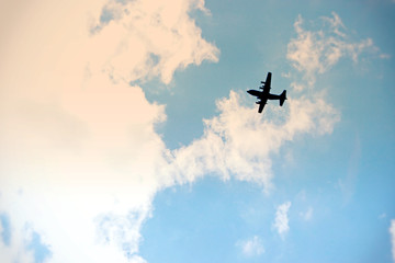 wojskowy bombowiec przelatuje nad miastem na tle niebieskiego nieba - obrazy, fototapety, plakaty