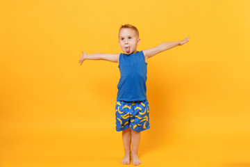 Smiling fun kid boy 3-4 years old wearing blue beach summer clothes isolated on bright yellow orange wall background, children studio portrait. People, childhood lifestyle concept. Mock up copy space.