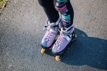 Two young girl standing on roller skates with protection on the knees in park and hold hands