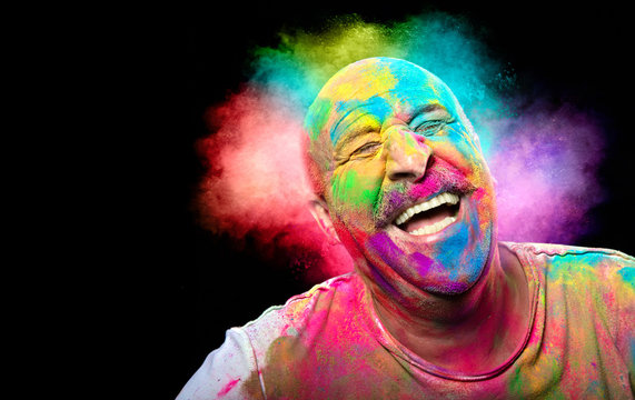 Bald smiling man with colorful face having fun. Colors festival