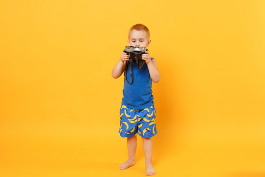 Kid boy 3-4 years old in blue beach summer clothes hold retro camera isolated on bright yellow orange wall background children studio portrait. People childhood lifestyle concept Mock up copy space.