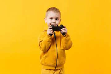 Little kid boy 3-4 years old wearing yellow clothes hold in hand joystick pc games isolated on orange wall background children studio portrait. People childhood lifestyle concept. Mock up copy space. © ViDi Studio