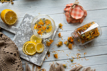 Tea and bottle with dried calendula on the white background