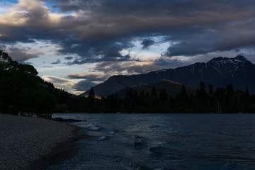 calm landscape during sunset with dramatic sky over lake and mountain range
