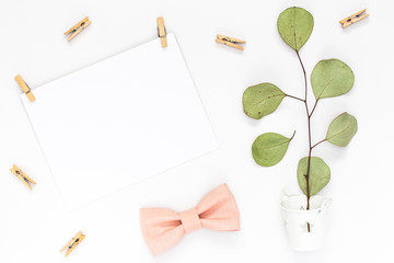 Top view on Beautiful greeting card idea with area for your text with sprigs and leaves, wooden clothespins, and a powdery bow tie copyspace, topview, mockup, flatlay