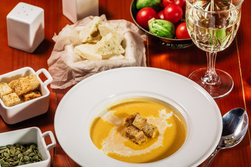 Pumpkin cream soup with croutons, baked chickpeas, sesame, parsley on a brown wooden background. Baked chickpeas with spices. Useful dietary snacks. Served with white wine and cheese
